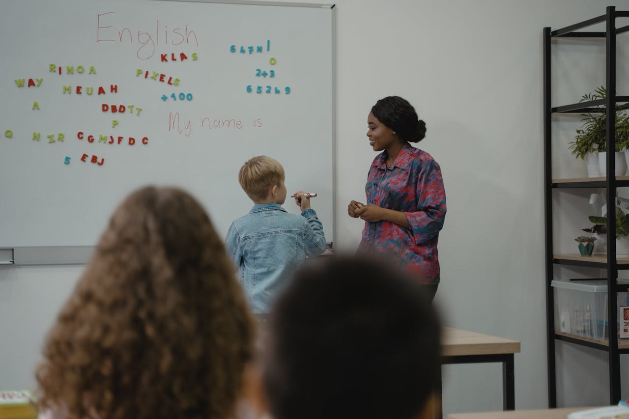 A Student Standing in front of a Class with the teacher.
