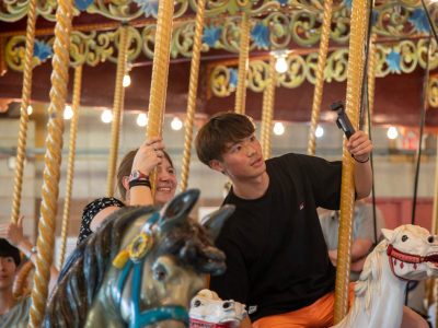 two people riding a carousel taking a selfie