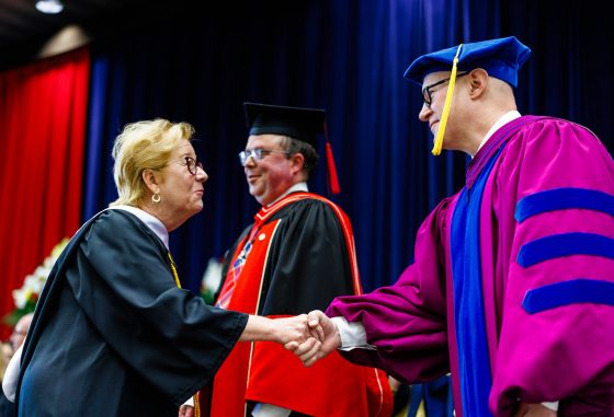 20260610_FOSSHUMAft_SL_9 A graduate shakes hands with a university official while crossing the stage during a Brock University Convocation ceremony.