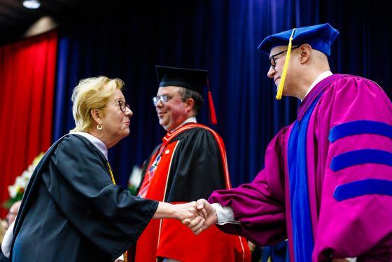 20260610_FOSSHUMAft_SL_9 A graduate shakes hands with a university official while crossing the stage during a Brock University Convocation ceremony.