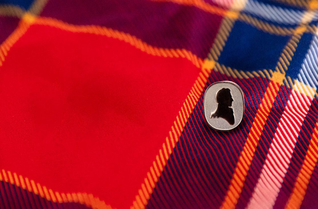 Brock University red tartan with Alumni Relations lapel pin in foreground.