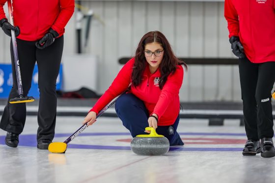 A woman curler about to throw the stone.