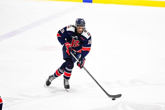 Brock hockey player in mid ice with puck.
