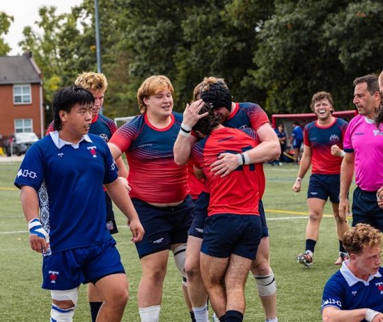 Men's rugby team members celebrating after a win with a group hug.