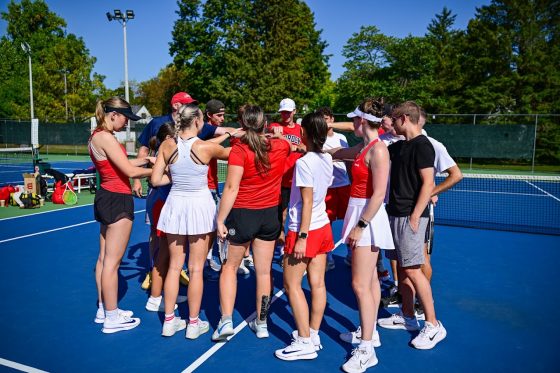 Tennis players gather together for a team cheer.