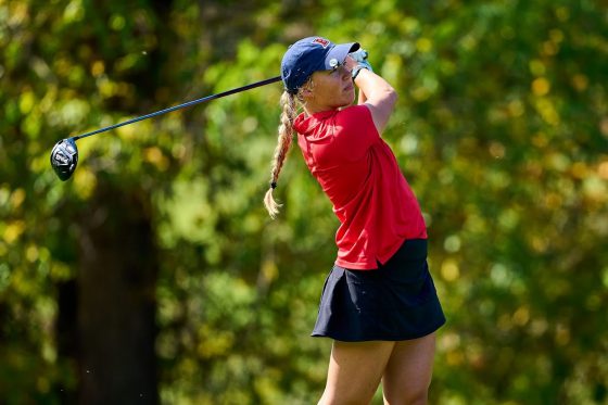 A picture of a woman who just shot a golf ball.
