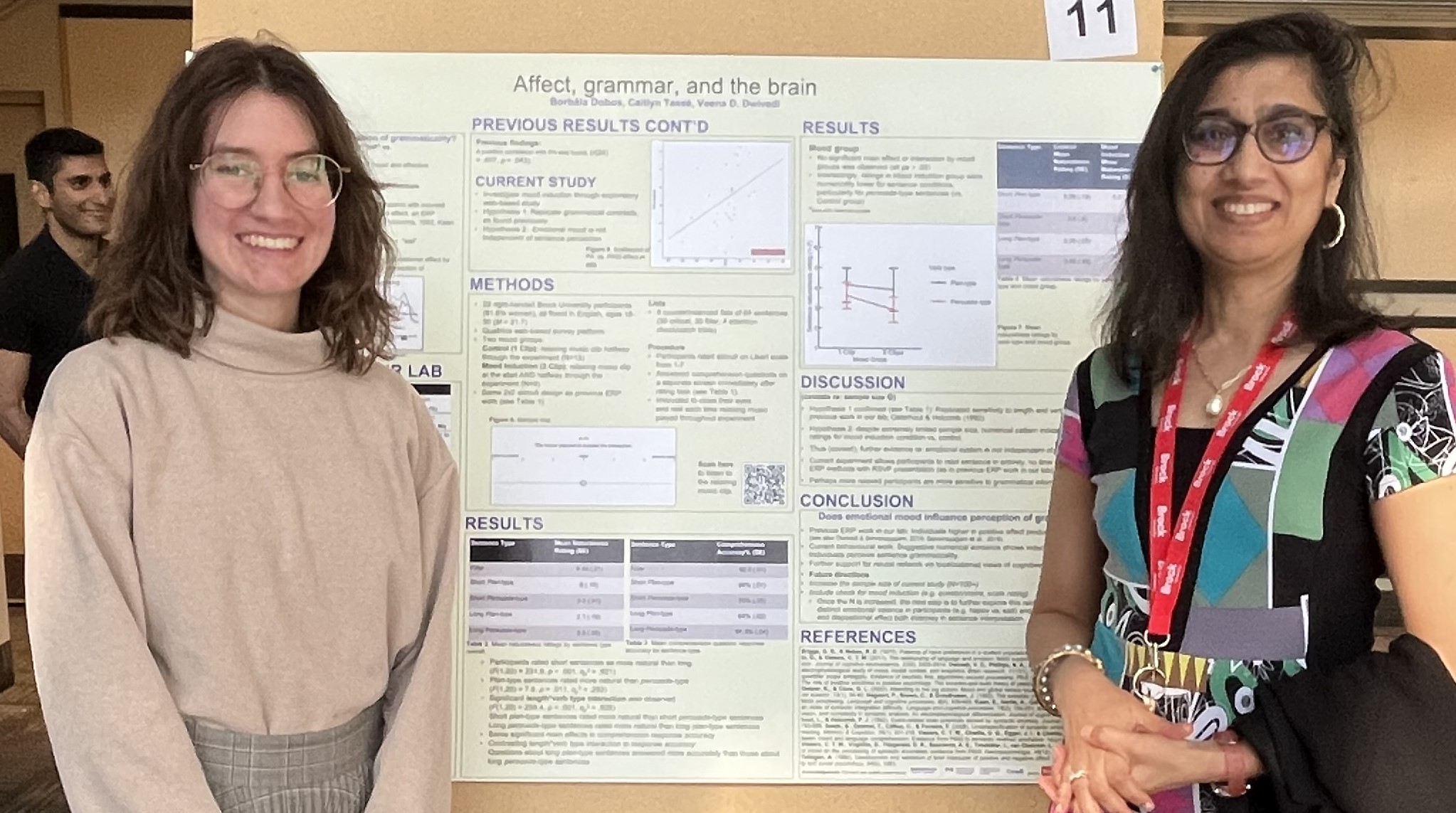 Borbála Dobos and Veena Dwivedi stand beside a research poster.