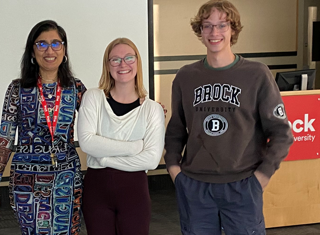 Veena Dwivedi, Faith Martin and Ethan Busch standing in front of a Brock University lectern.