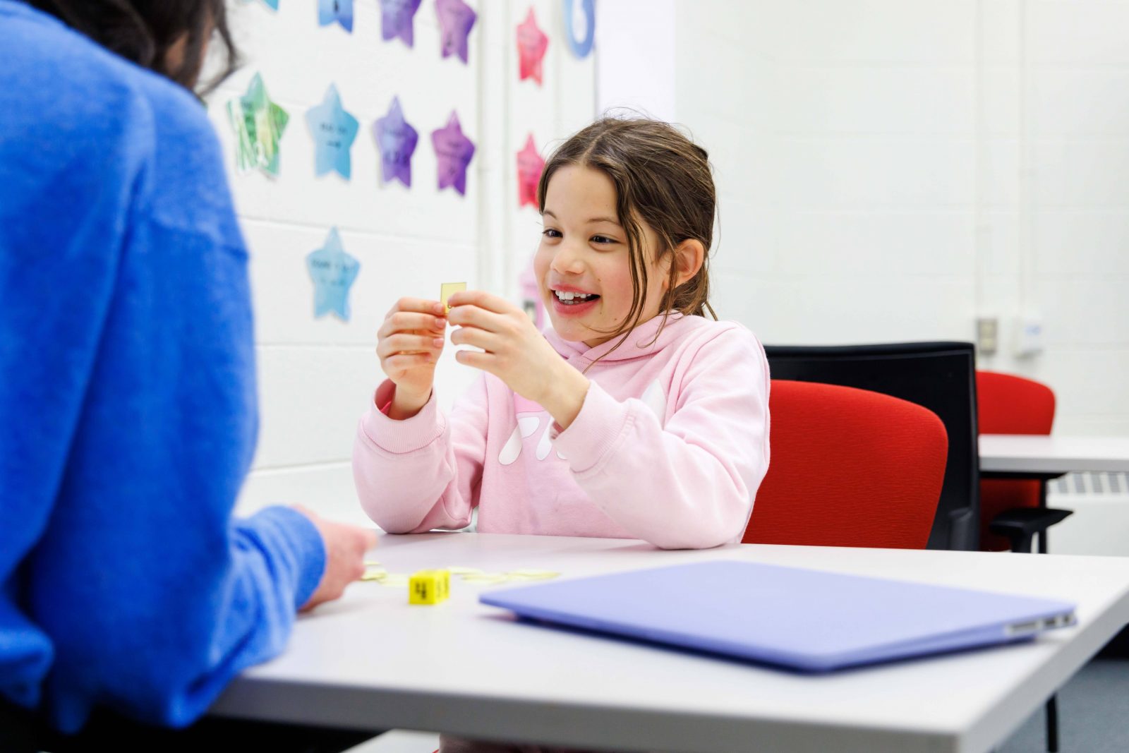 A child sits at a table with a teacher. 