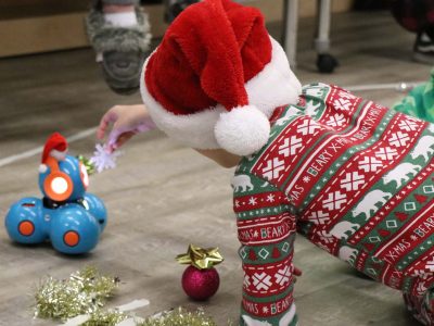 An elementary school student plays with a robot at the Holiday Extravaganza