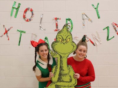 Brock volunteers pose with a Grinch decoration at the Holiday Extravaganza
