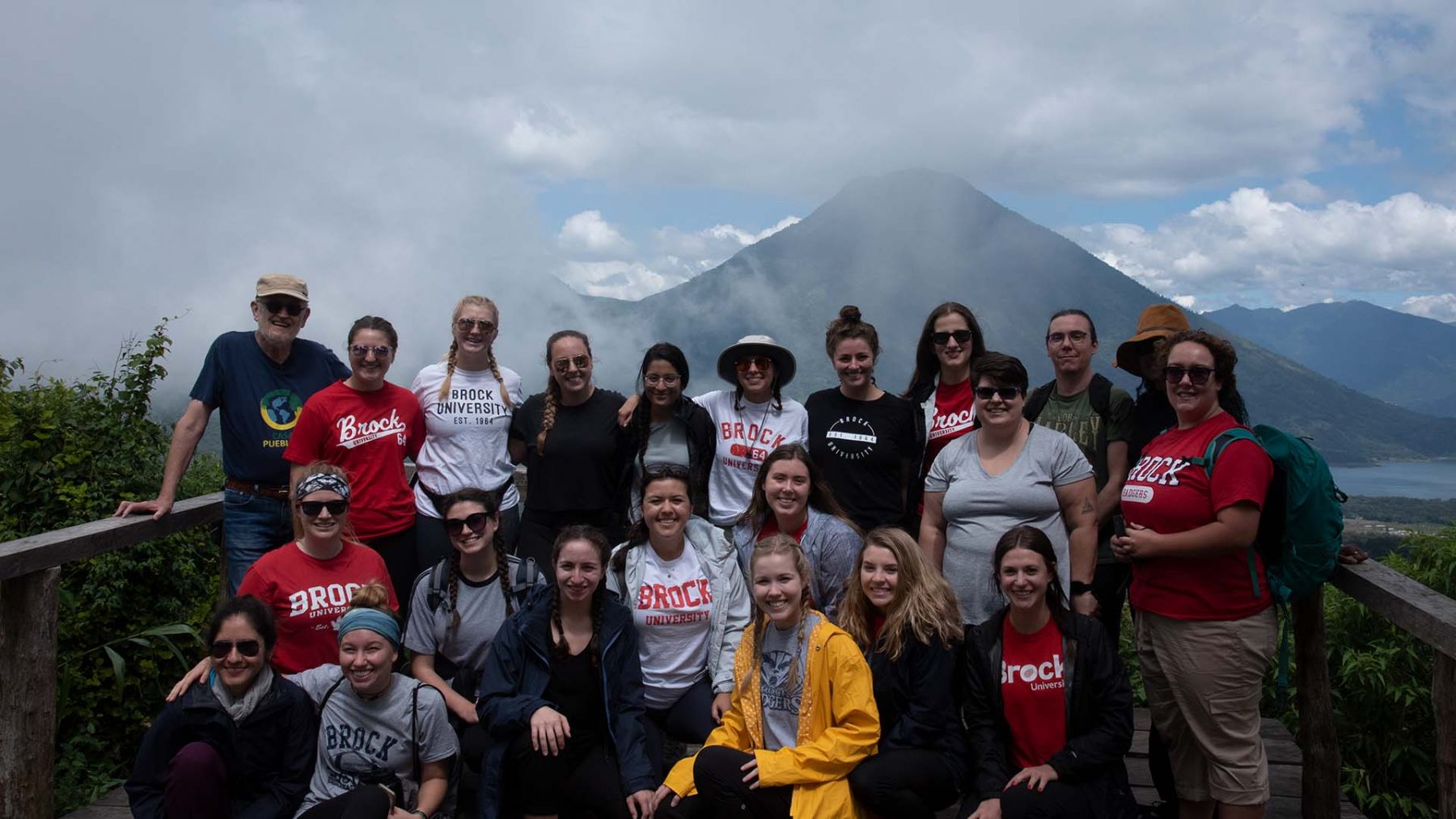 A group of 19 Brock students, along with two faculty members and a staff member, are pictured in front of Volcan de San Pedro.