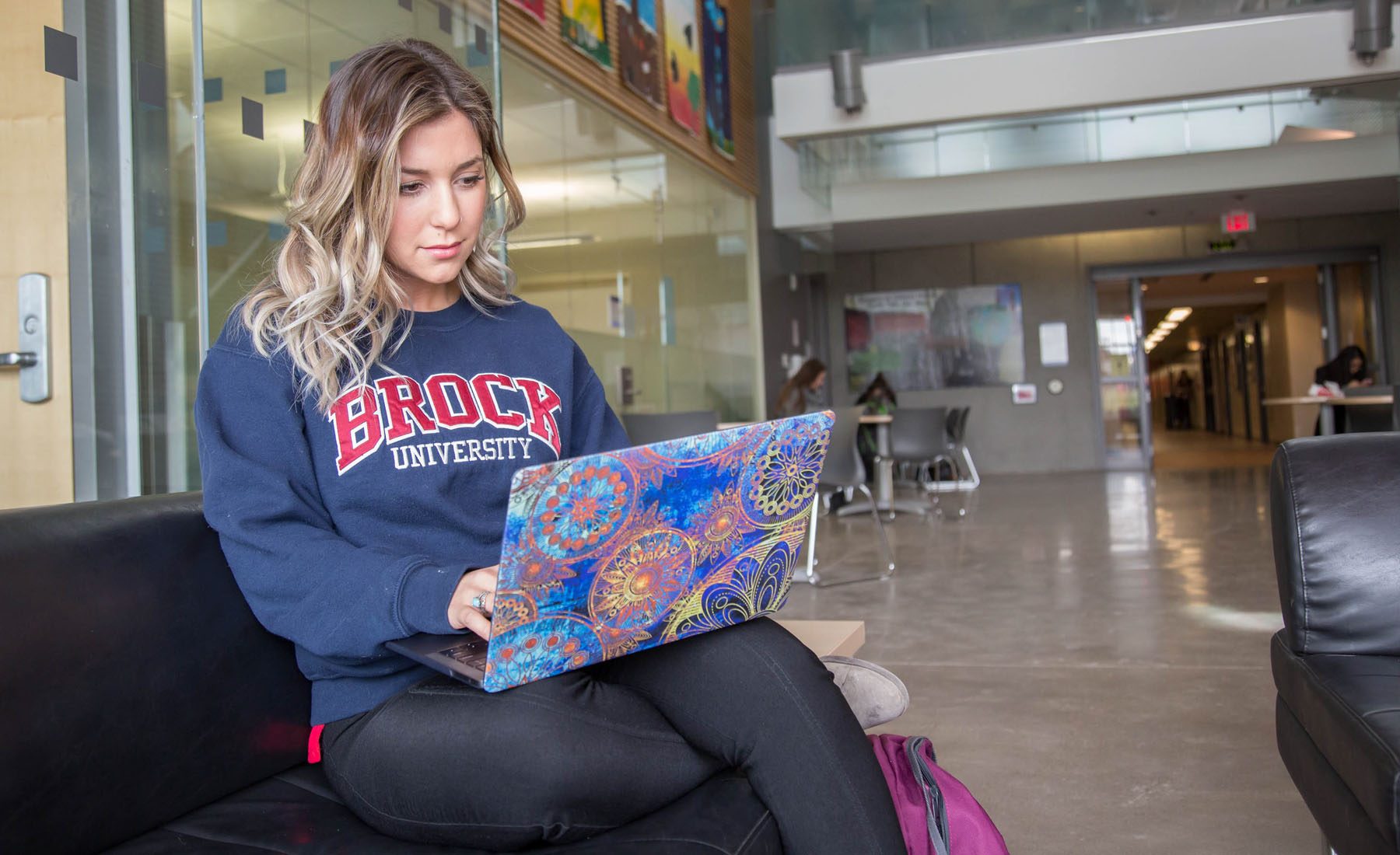 Female student studies on a couch with laptop at Brock University 