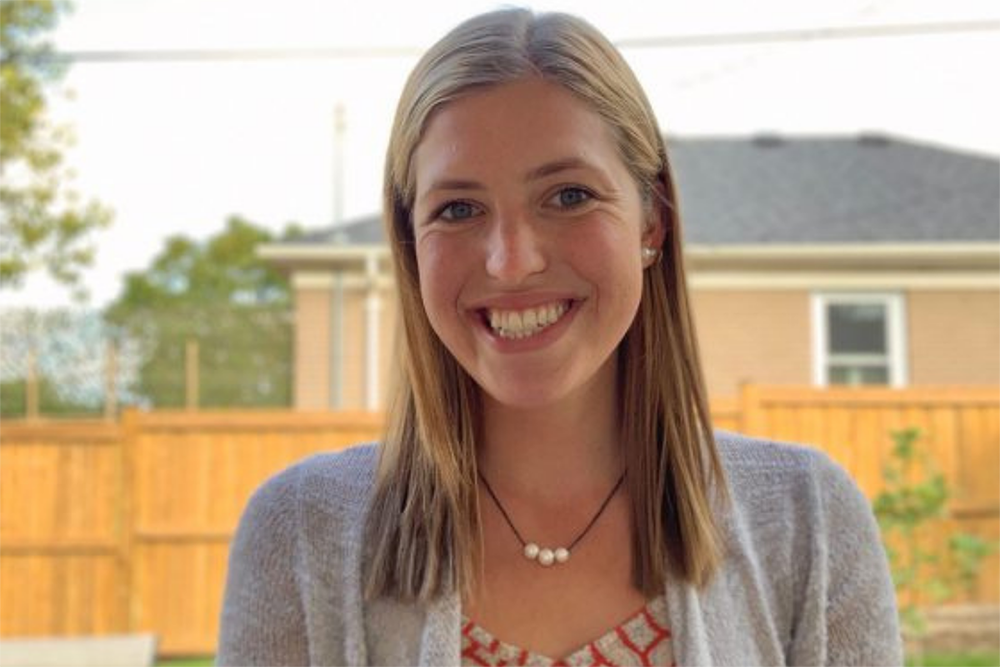 Allison Clark standing in a backyard with a fence and house in the background.