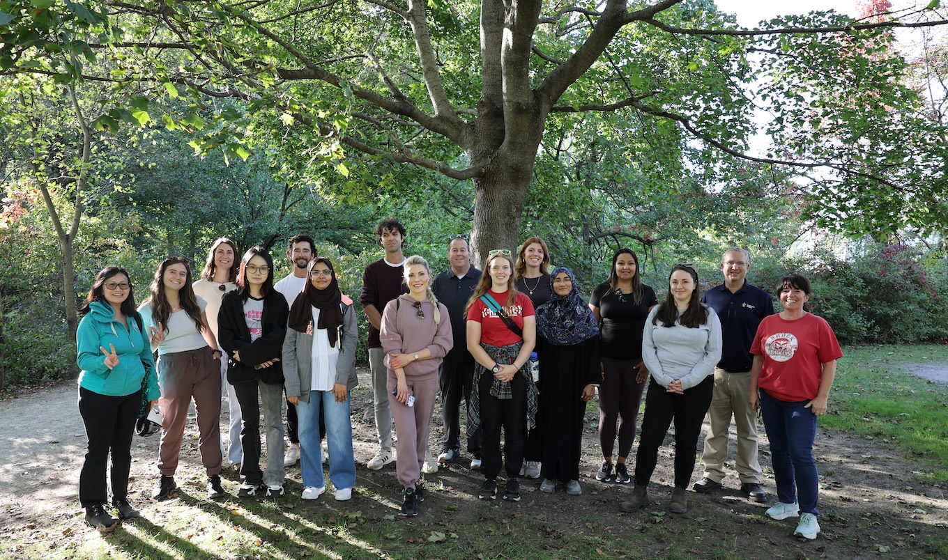 A group of people standing in front of a tree.