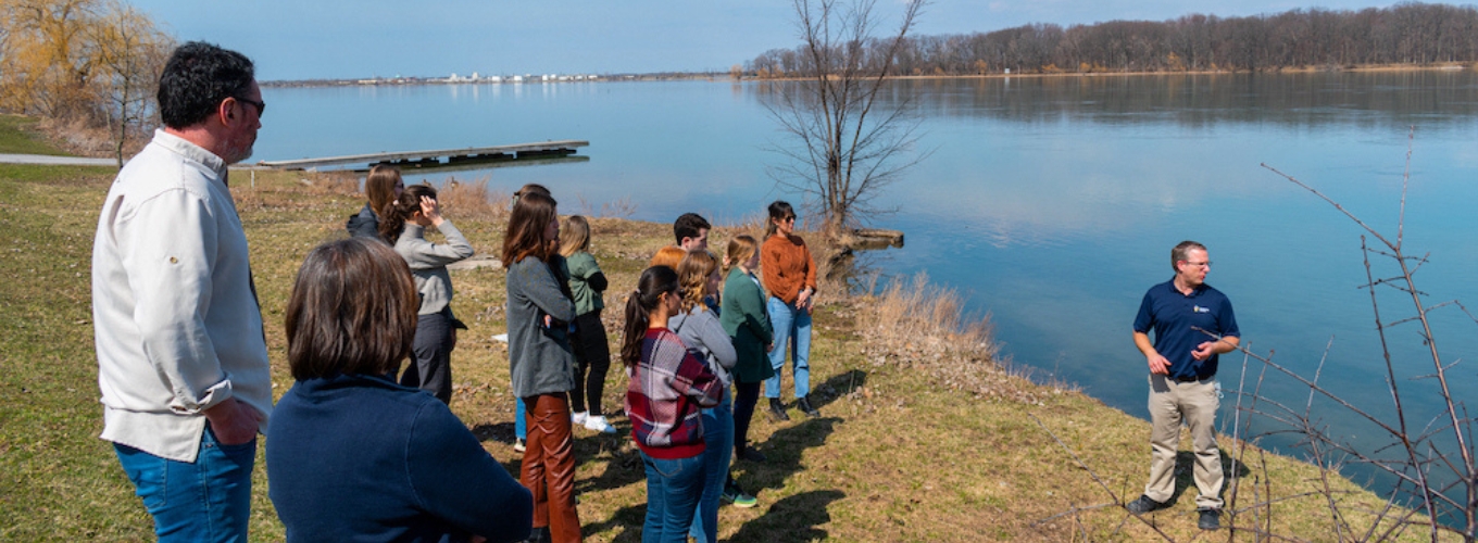 A group of students and professors standing at a waterfront.