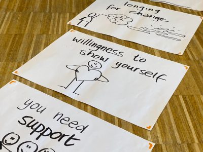 Pieces of paper with handwritten words of affirmation and artistic drawings spread across a table.