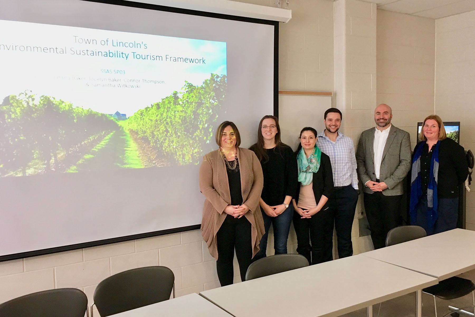 Students and faculty posing in front of screen