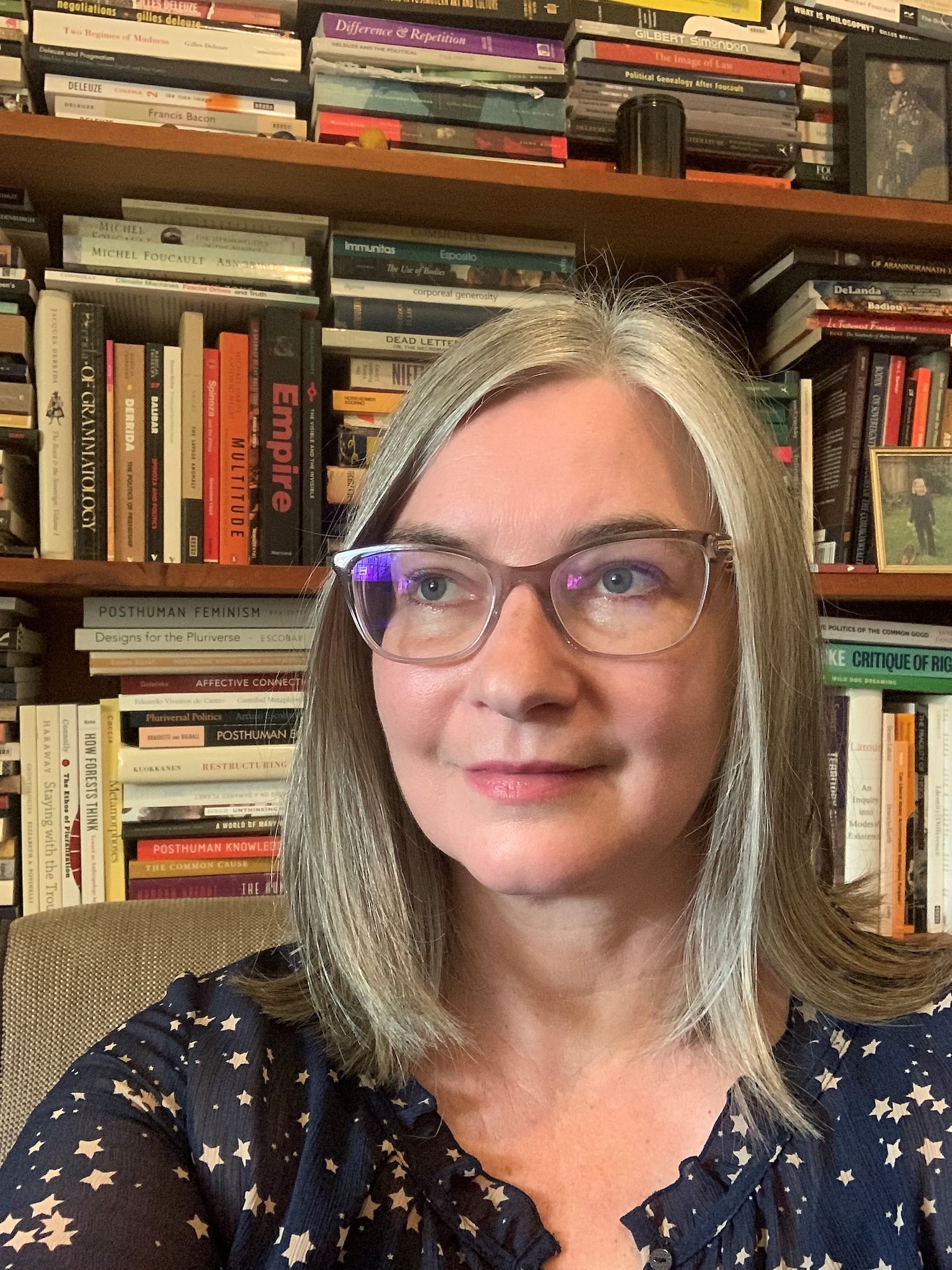Simone 2022 Simone Bignall in front of bookshelves.