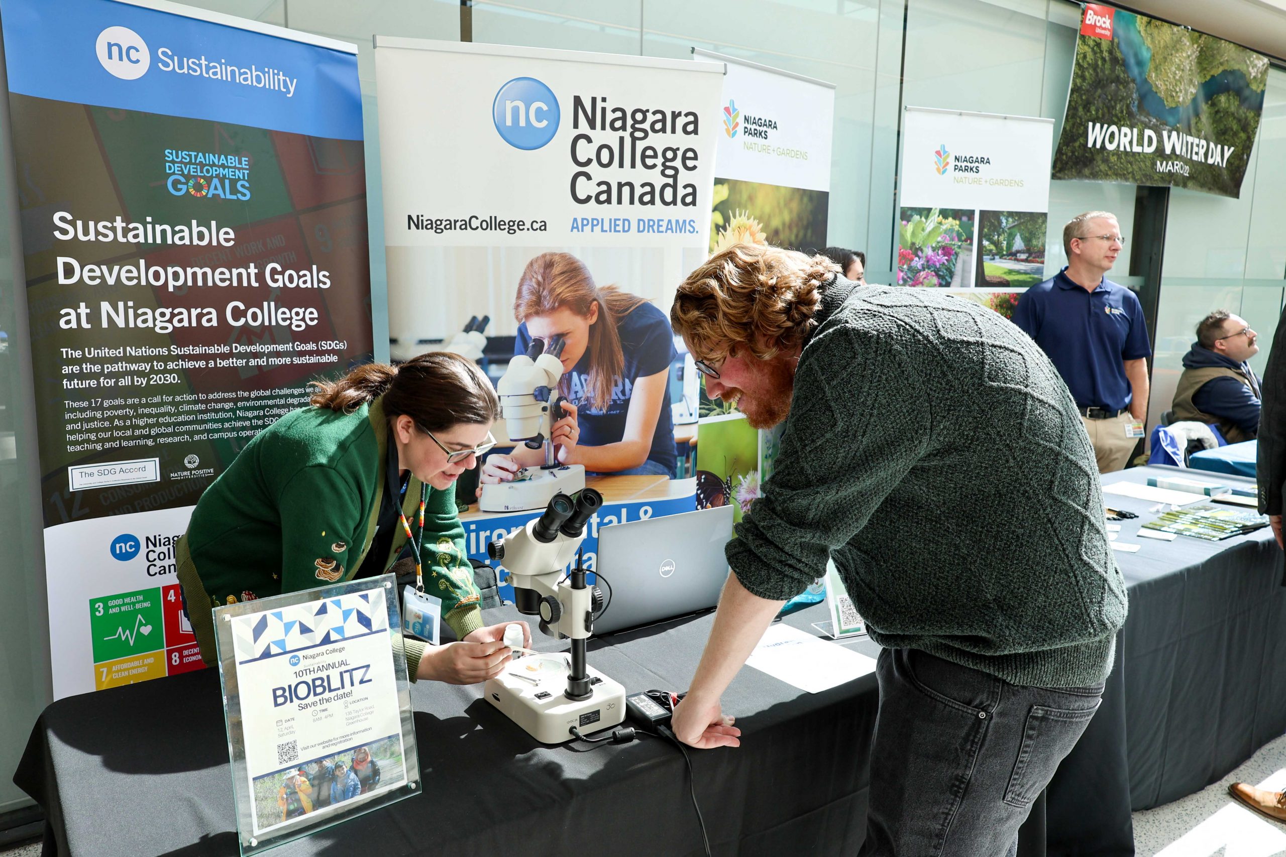 Alumnus Matthew Summerville prepares to view slides through a microscope at the Niagara College booth.