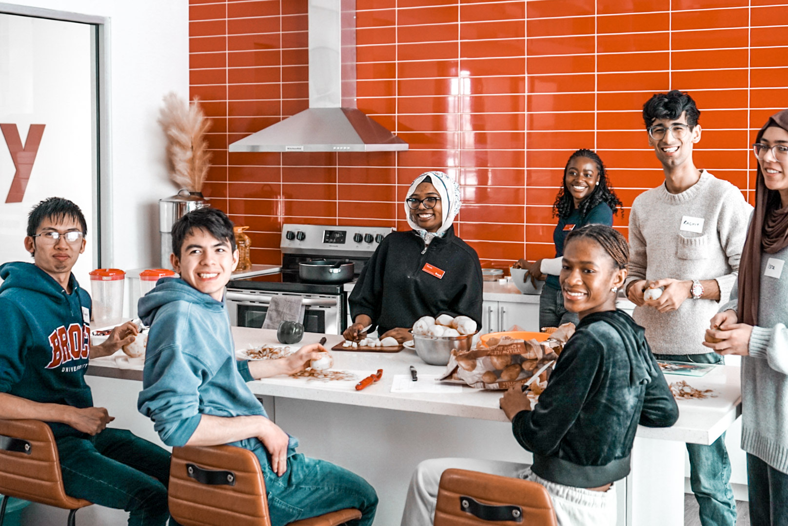 Students gather around a kitchen island to cook together
