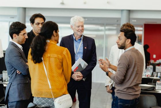 A grout of alumni networking with the Dean of the Goodman School of Business