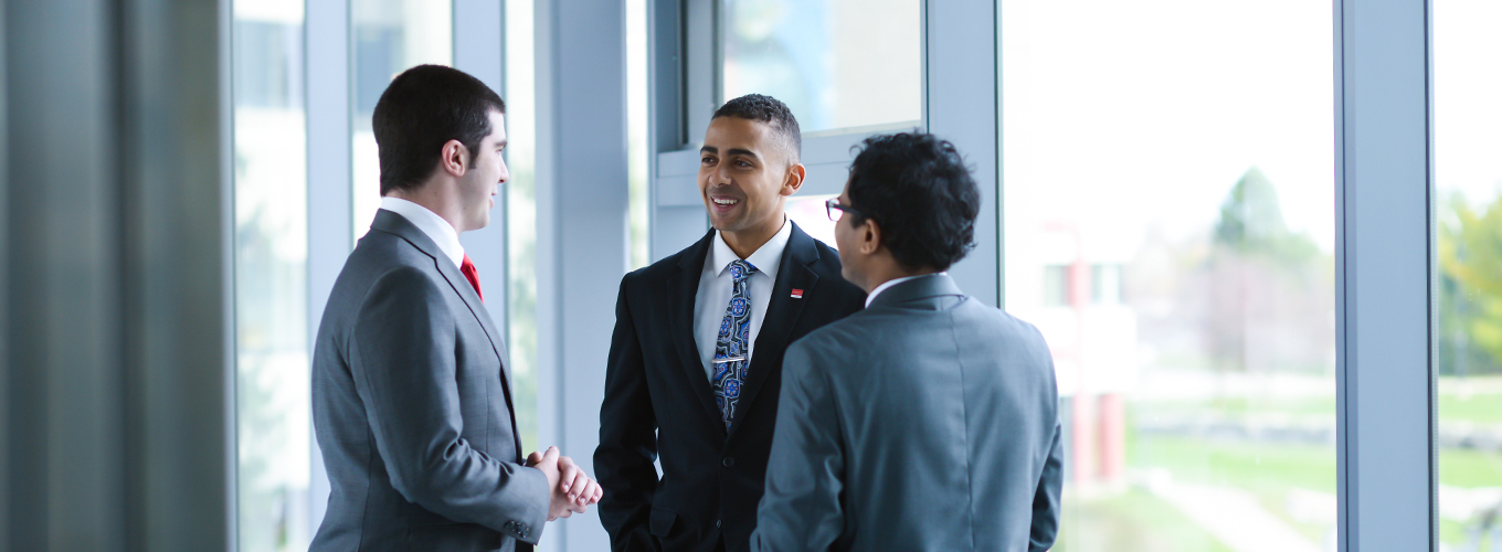 Three students talking in the Goodman School of Business building