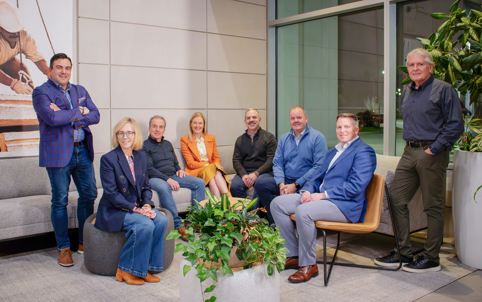A group of alumni pose for a photo in a modern office building