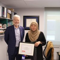 Photo of Parunchana Parcharn holding her graduate professor of the year award beside Dean Barry Wright