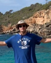 Person stands by a body of water with their hands outstretched, smiling