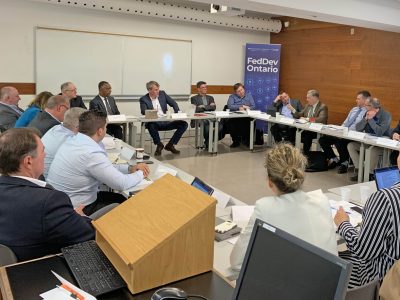 group of people in discusssion sitting around a large square table