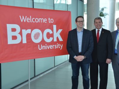 delegates in front of a building with a Brock University Logo banner
