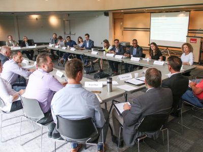 group of people in discusssion sitting around a large square table