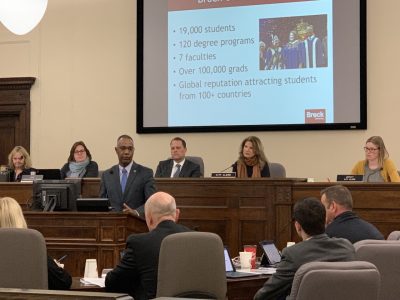 people in a room meeting in front of a screen with a presentation on it