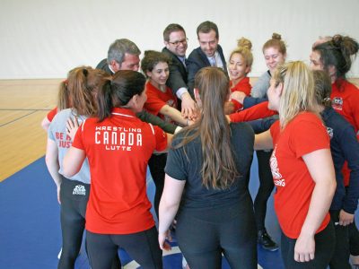 students in a gym with hands put into a circle chear