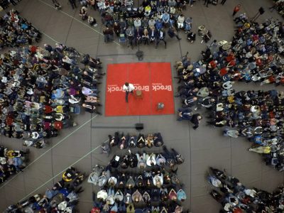 Arial photo of people looking at a red stage with a male speaker on it