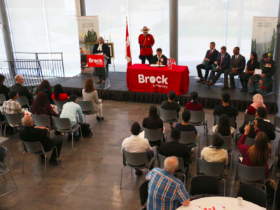 people gathered in room sitting in chairs facing a red table presentation