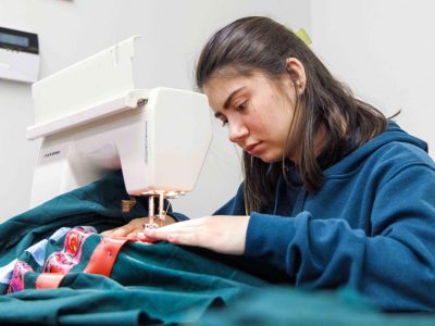 A women uses a sewing machine to make a ribbon skirt.