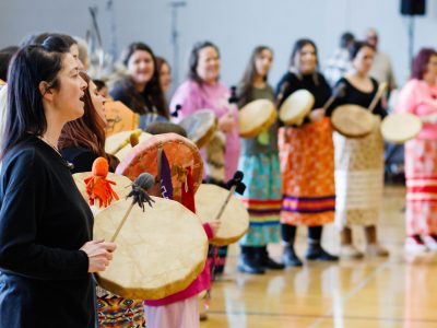 A group of women sing and play hand drums.