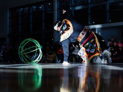 A male dancer in regalia dances with hoops.