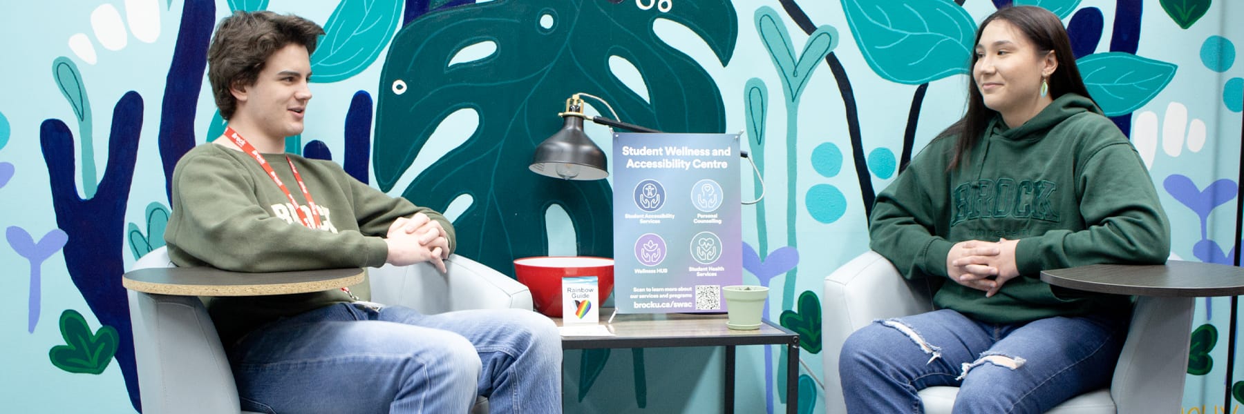 two students talking in front of the mural in the Wellness Hub at Brock University