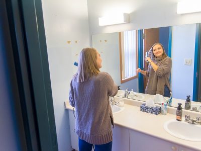Student using mirror in Village bathroom