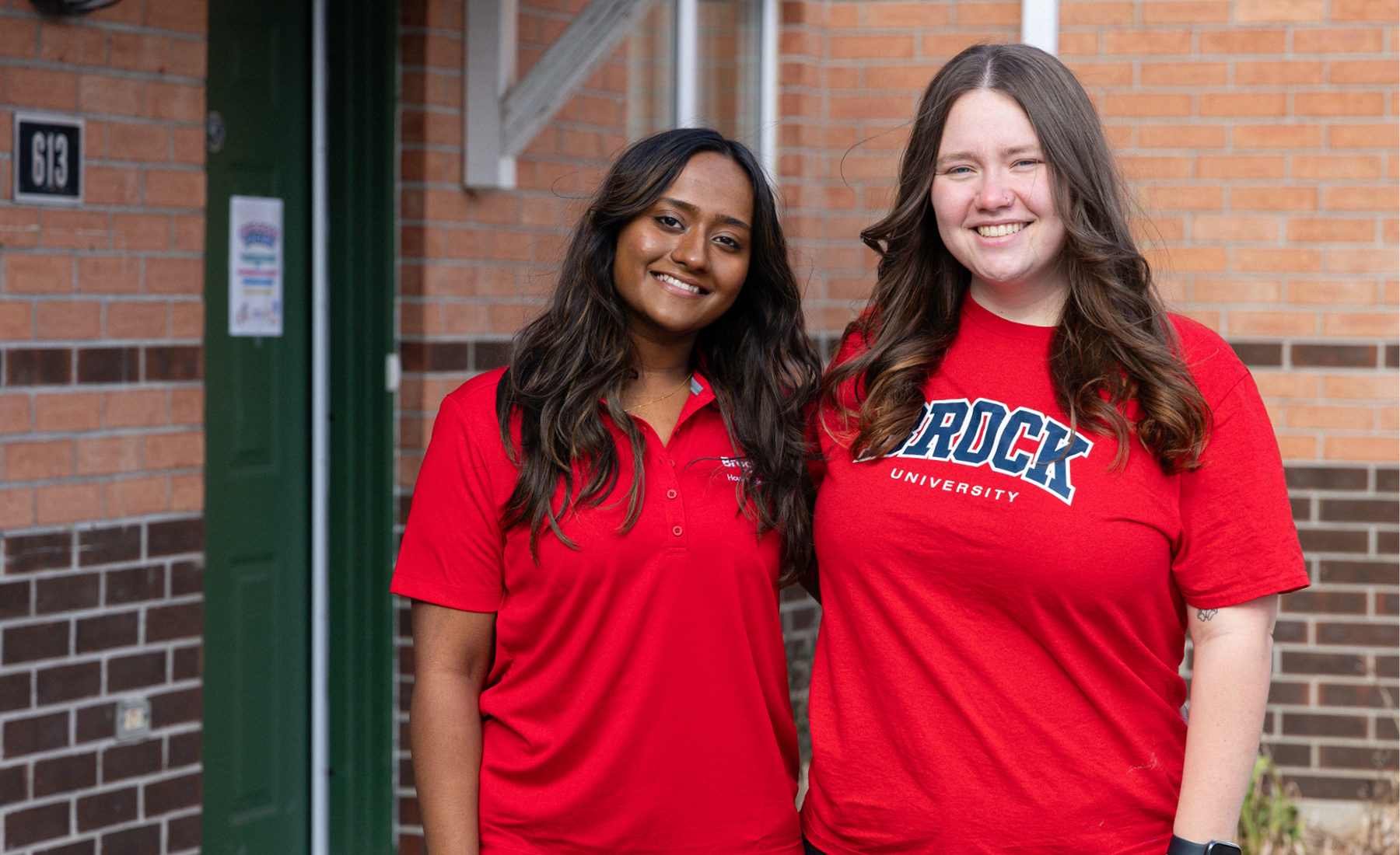 two rls staff members stand outside village residence 