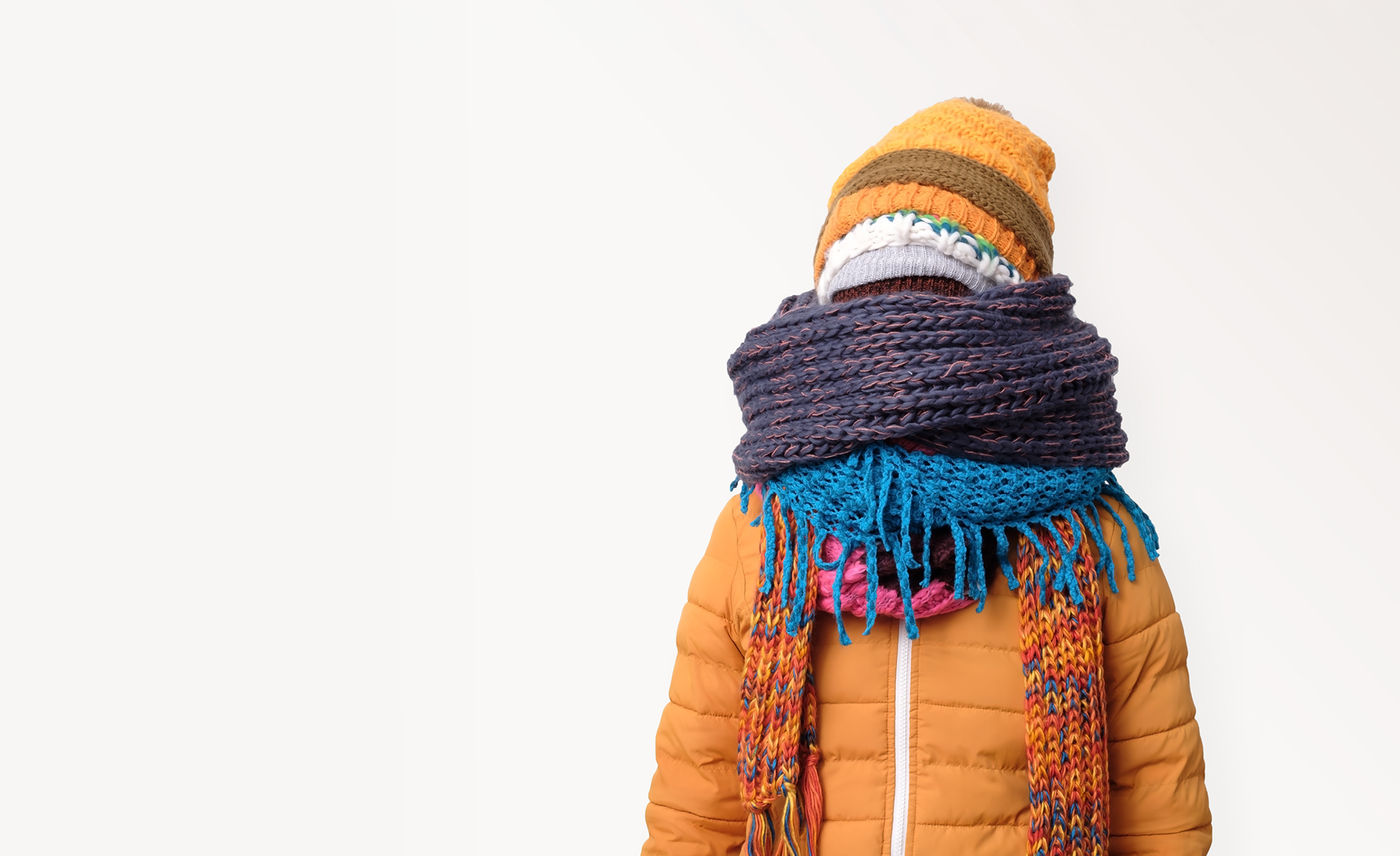 a person wearing winter coat and hat and several scarves covering face 