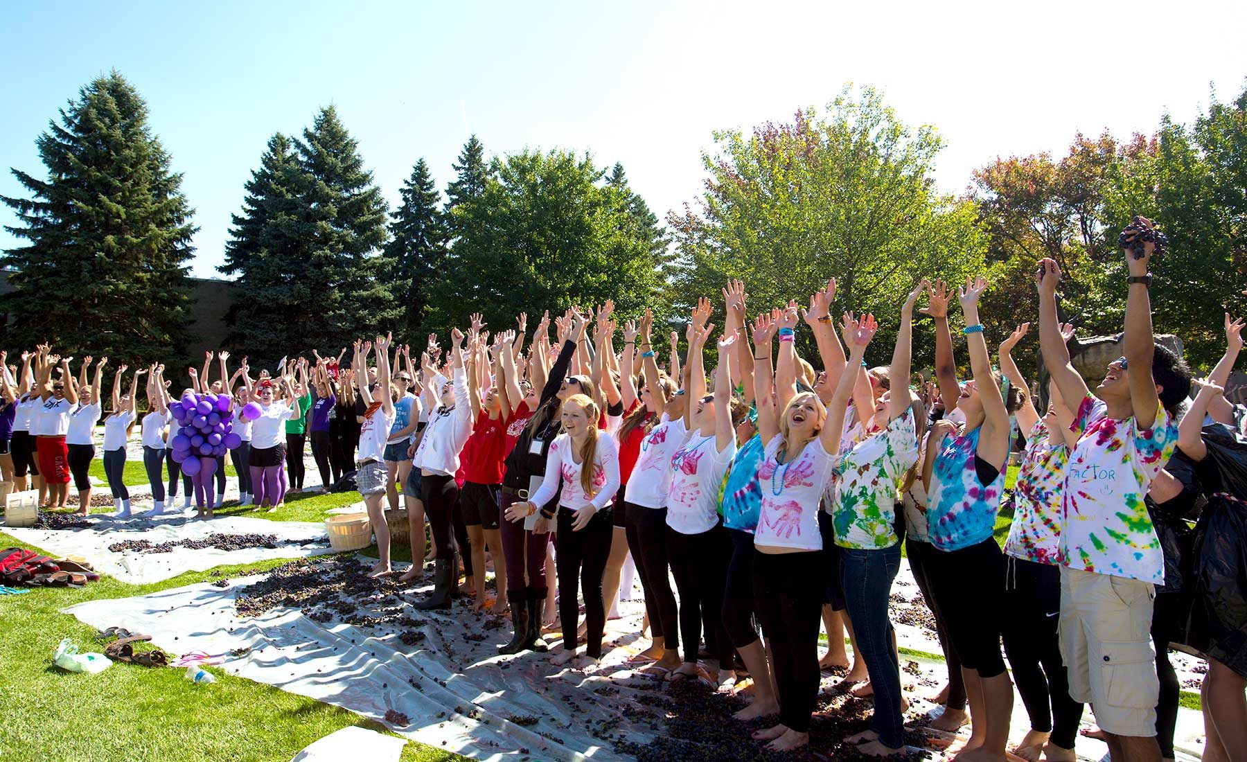 Large group of students in line with their hands in the air at Grape Stomp event