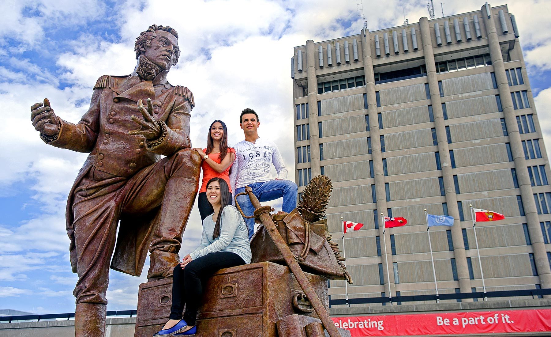Three students standing with Sir Isaac statue
