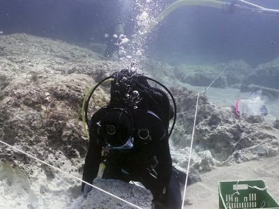 scuba diver underwater lifting a large stone