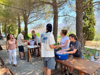 7 students at a table outside sifting through water in buckets in Gournia