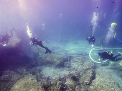 5 scuba divers documenting area underwater and readying a lift with balloons