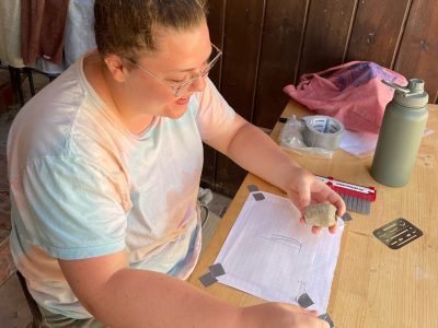 student drawing details of an artifact she is holding